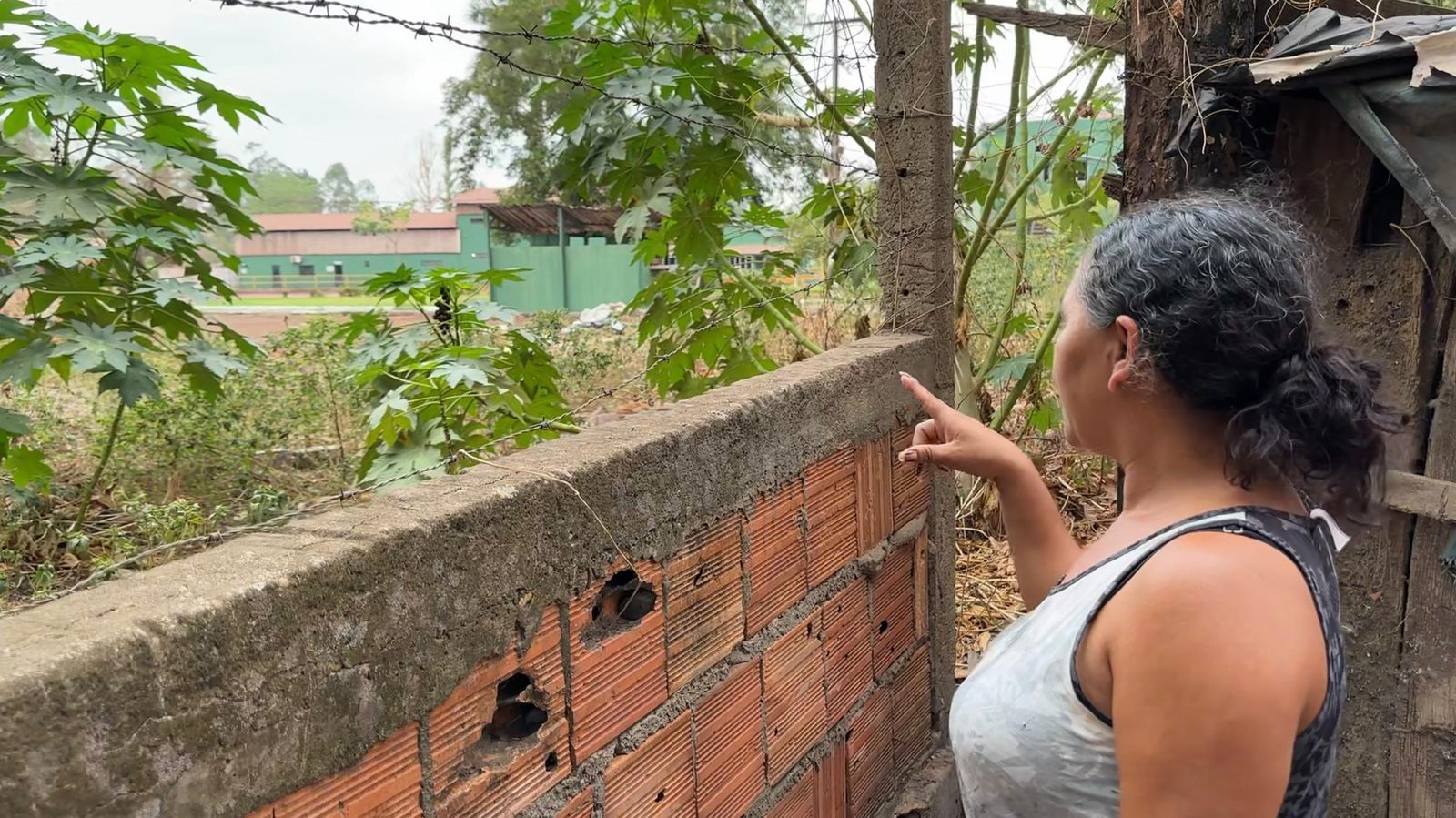 Ana Maria Sousa no quintal de sua casa em Piquiá de Baixo, com uma empresa visível ao fundo